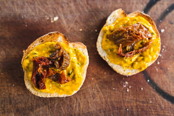 simple food ingredients, bread slices with sweet potoato and kale dip topped with sundried tomatoes