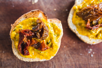simple food ingredients, bread slices with sweet potoato and kale dip topped with sundried tomatoes