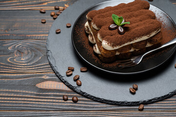 Classic tiramisu dessert on ceramic plate on wooden background