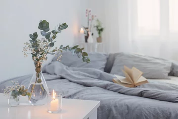 Foto op Plexiglas burning candles and eucalyptus in glass vase in white bedroom © Maya Kruchancova
