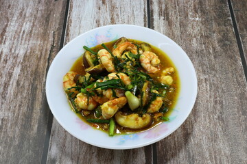 Traditional fried and stirred fresh peeled shrimp with cutting mushroom, basil and turmeric powder on the plate. Famous hot and spicy seafood menu in Asia restaurant. 