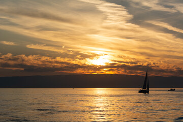 Couché de soleil sur le lac Léman avec bateau à voile en silhouette