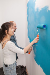 Cheerful couple painting the wall during improvement. Couple redecorating together. Apartment redecoration and home construction while renovating and improving. Repair and decorating.
