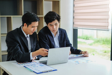 Two young asian businessman talking and working together at office.