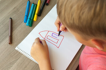 A small child draws a house with markers in the album. Step-by-step instructions.