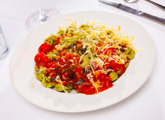 Appetizing tortellini stuffed with mix of spinach and cheese served with baked red sweet pepper in tomato sauce. Italian cuisine