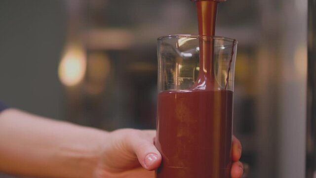 Closeup shot of pouring chocolate cake mixture into transparent glass. Making Chocolate Layer Cake. Culinary concept. Slow motion