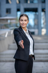 Elegant woman in a suit stretching her hand in greeting