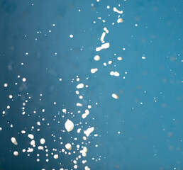 Splashes of white milk isolated on a blue background.