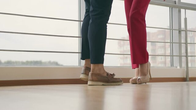 Legs of a man and a woman approaching each other indoors. Man and woman go to meet each other.