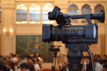 Video camera close-up of a conference room with a background of people, blurred background