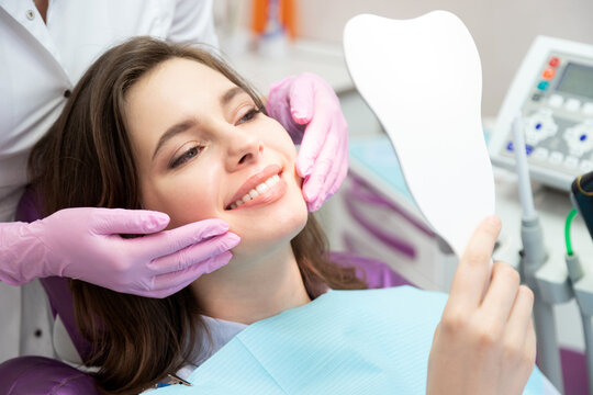 Happy patient after tooth treatment at dental clinic  look at mirror enjoy healthy enamel.