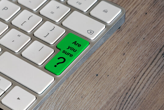 Computer keyboard with a question on the lime green enter key on an oak table background