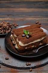 Classic tiramisu dessert on ceramic plate on wooden background