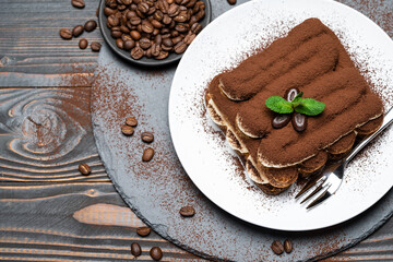 Classic tiramisu dessert on ceramic plate on wooden background