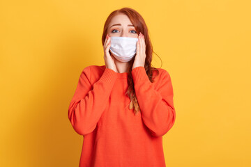 Beautiful red haired woman clings to her head and being shocked by spreading of corona virus. Red...