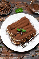Classic tiramisu dessert on ceramic plate on wooden background