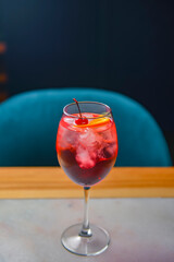 A glass with the red citrus cocktail. Alcohol summer beverage in a wine glass. Refreshing drink with ice.