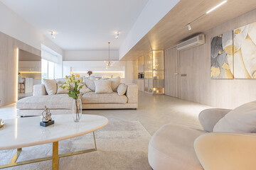 trendy modern interior design of a large studio in white and beige colors with large floor-to-ceiling windows. area of ​​white kitchen with an island and a recreation area