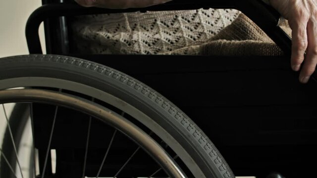 Hands of old woman on wheelchair