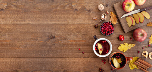 Autumn snack with tea, berries and apples on a wooden background. Две чашки чая и нарезанные ломтиками яблоки. Вид сверху. Баннер.