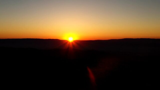 Majestic sunset aerial view over south Jerusalem mountains. Silhouette landscape with sunlight flare behind the horizon mountains of judea and samaria settlements west bank.