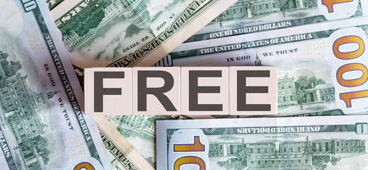 Concept words FREE on the wooden blocks on a beautiful background from dollar bills.