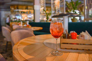 A glass with the red citrus cocktail. Alcohol summer beverage in a wine glass. Refreshing drink with ice.