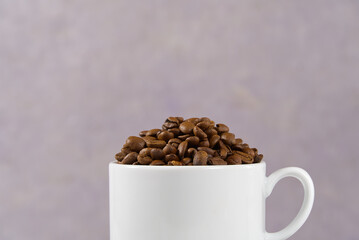 International day of coffee concept. close-up white coffee cup full of coffee beans on old rose Background.