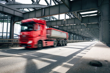 Red truck driving over an industrial style bridge