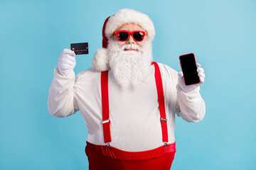 Fototapeta na wymiar Portrait of his he nice attractive confident white-haired Santa holding in hand demonstrating credit card device order shop buy web isolated bright vivid shine vibrant blue color background