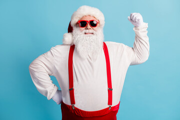 Fototapeta na wymiar Portrait of his he nice attractive cheerful content fat overweight white-haired Santa demonstrating muscles isolated over bright vivid shine vibrant blue color background