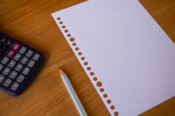 blank paper, ballpoint, and calculator for mockup concept on wooden board. finance, education background