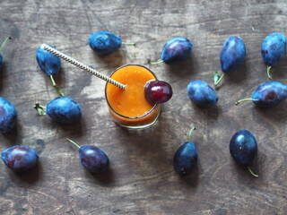 Natural products concept.Glass plum juice or smoothie with paper straw on a wooden natural table with fresh plums.