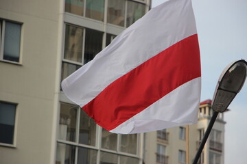The white-red-white flag of Belarus flies over a living apartment in the street