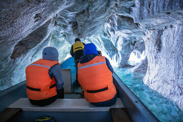 Couple of tourists visit the marble caves aboard a boat on the General Carrera lake. Puerto Rio...