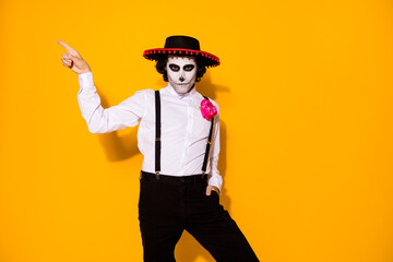 Photo of creepy guy direct finger empty space hand pocket show danger promotion wear white shirt rose death costume sugar skull sombrero suspenders isolated yellow color background