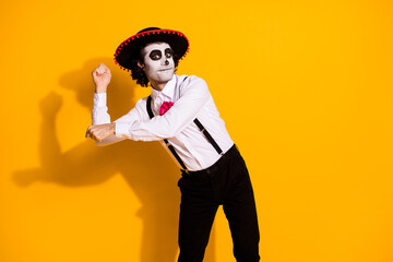 Photo of spooky ghost monster guy dancing latino national dance pretend hold maracas festival guy wear white shirt rose death costume sombrero suspenders isolated yellow color background