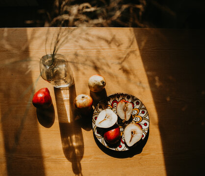 still life with a bottle. pears on a wooden table. pears on a wooden table bathed in the sun. picnic in the summer garden. flowers and fruits on a wooden table. sunny shadows on the kitchen table