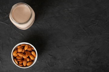 Obraz na płótnie Canvas Almond milk in glass with almonds on concrete background with copy space