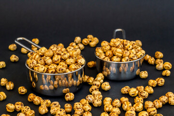 Yellow chickpeas with mini stainless steel containers on black background 