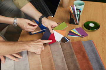 Close-up of fashion designers examining the samples and choosing the suitable color of fabric at office