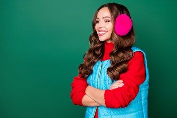 Profile photo of cute lovely young lady folded hands self-assured cheerful look empty space waiting friend wear pink ear warmers blue vest red sweater isolated green color background