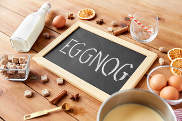 christmas and seasonal drinks concept - eggnog word written on chalkboard, ingredients and aromatic...