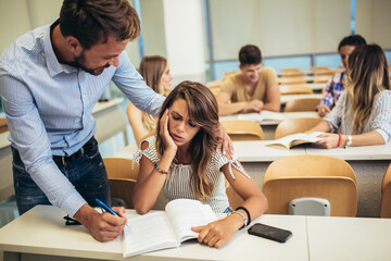 Fototapeta premium Professor helping a student in classroom at college