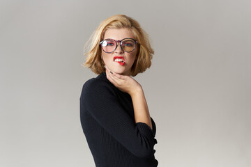 Blonde girl with glasses red lips black blouse cropped view glamor light background studio