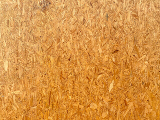 Top view of OSB brown wood chips veneer texture surface wall background.