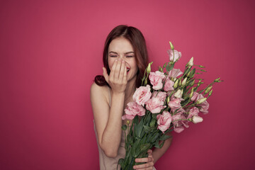 beautiful woman with a bouquet of flowers on a pink background in a light dress makeup model