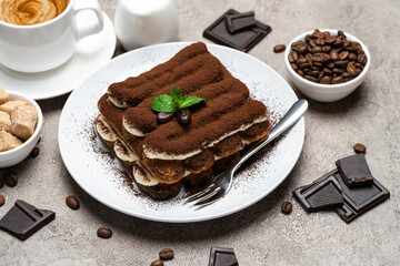 Classic tiramisu dessert, cup of coffee, sugar and milk on concrete background