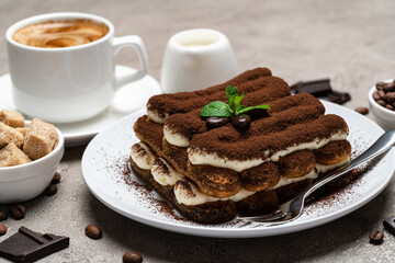 Classic tiramisu dessert, cup of coffee, sugar and milk on concrete background